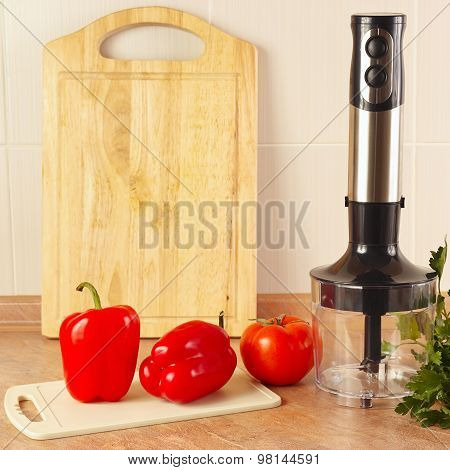Red bellpepper with tomato and a blender on kitchen table