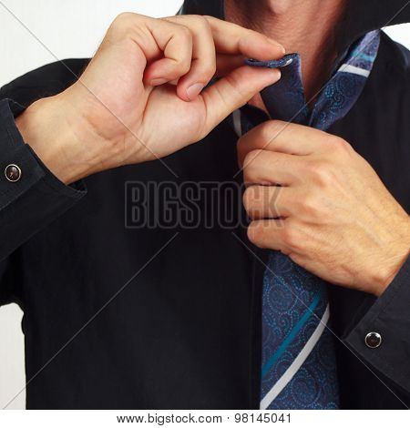 Man tying his tie over black shirt closeup