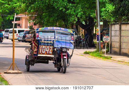 Dumaguete Philippines - 13 May 2017: National Philippine transport tricycle on city street. Tourist transport. Transport traffic in Philippines. Traditional transport. Custom motorbike. Green city