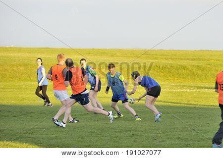 Claddagh Galway Ireland june 2017 friends playing touch rugby in the free public south park fields a girl executing a pass.