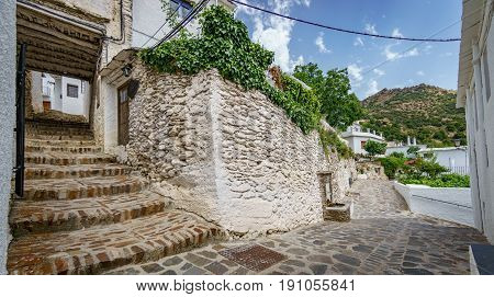Wide angle view of street and stairs house entrance with plantpots in Capileira, Granada, Spain
