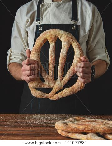 Baker's hands hold fougas bread