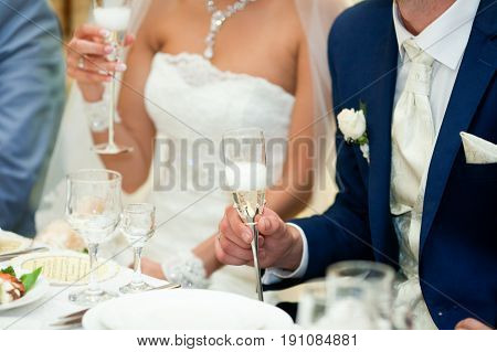 Stylish bride and groom hold in their hands steel champagne flutes
