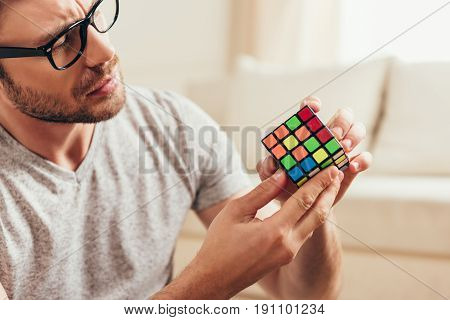 Close-up Portrait Of Serious Young Man In Eyeglasses Holding Rubik Cube
