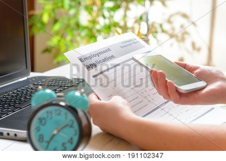 Blank employment application form in hands on a desk