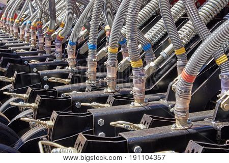 Fragment of a seeder with grain feeding hoses and mechanisms for adjusting the tension of springs