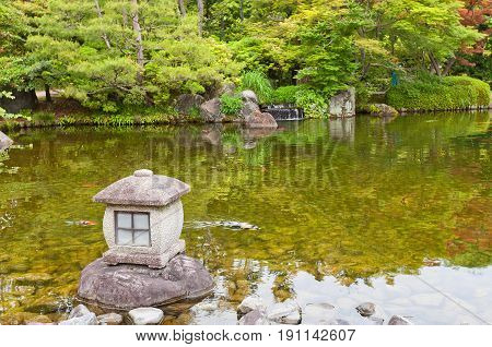 HIMEJI JAPAN - MAY 16 2017: Traditional stone lantern (toro) on the pond of Kokoen Garden near Himeji castle Japan. Garden was laid out in 1992 to commemorate 100 anniversary of Himeji city