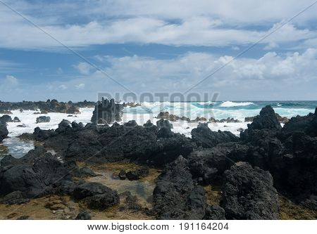 Black lava rocks line the shore at Keanae on the road to Hana in Maui, Hawaii