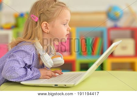 Portrait of adorable little girl using modern laptop