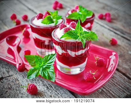 raspberry dessert with cream, fresh berries and mint in a glass
