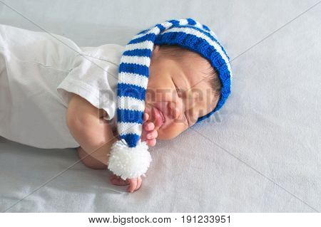 newborn in hat on white blanket asian baby stomach ache. Infant care teething pain colic ache concept