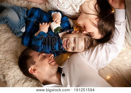 Happy young family lie on bed together. They laugh fun. Top view. Closeup.