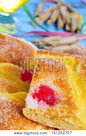 a plate with pieces of coca de Sant Joan, a typical sweet flat cake from Catalonia, Spain, eaten on Saint Johns Eve, on a rustic blue table, with champagne, firecrackers, confetti and streamers