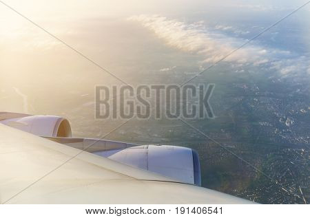Looking thru airplane 's window in the morning seeing wing of airplane white clouds and The City of Paris