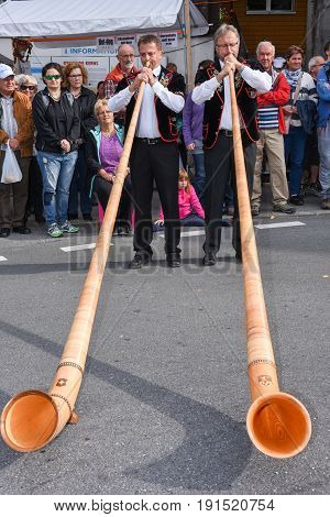 People Wearing Traditional Clothes And Playing The Alphorn At Kerns