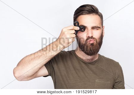 Young man holding and playing with fidget spinner. looking at camera. studio shot on white background.