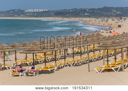 ALVOR, PORTUGAL - APRIL 23, 2017: People at the famous beach of Praia do Alvor, Algarve region, Portugal