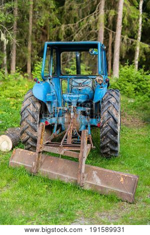 A blue tractor standing in a green forest