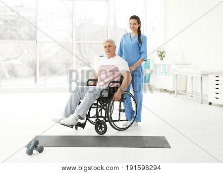 Senior disabled man with young orthopedist in rehabilitation clinic