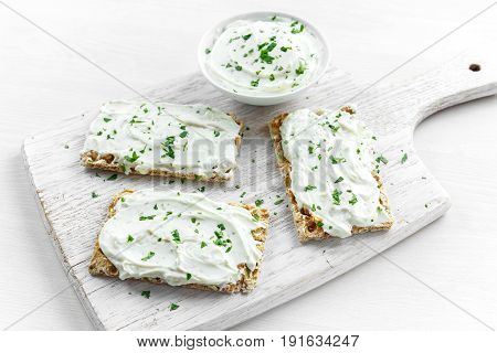 Homemade Crispbread toast with Cream Cheese and parsley on white wooden board background