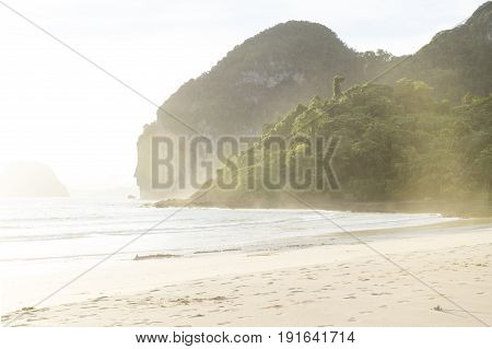 Sunlght on green mountains and sand at Hat Farang beach, Koh Mook, Thailand