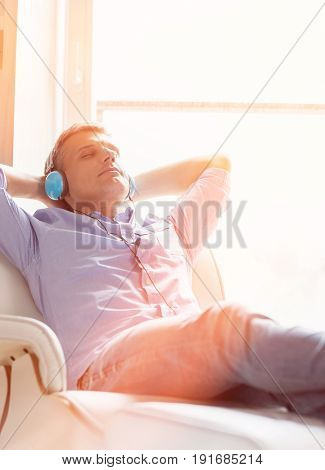 Relaxed Middle-aged man listening to music at home