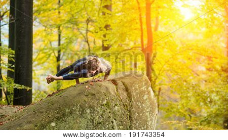 Sporty Fit Woman Is Practicing Yoga And Doing Asana Vakrasana In Autumn Park On The Big Boulder