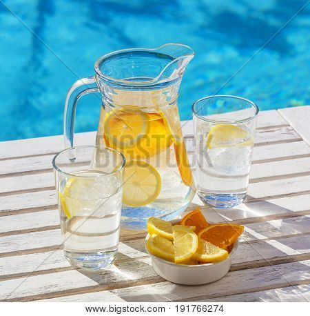 A jar and two glasses of refeshing ice water for hydration in hot weather.