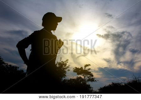 Hiker with backpack relaxing on a rock and enjoying sunset looking away. Silhouette of a young woman on the mountain peak. successful concept. Tourist backpacker traveller in Thailand.