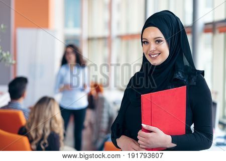 Arabian business woman with hijab holding a folder.