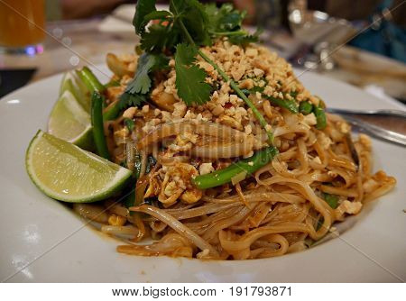 Chicken Padthai dish with lime slices
A delicious dish of padthai served with lime slices in a round plate, with herbs on top