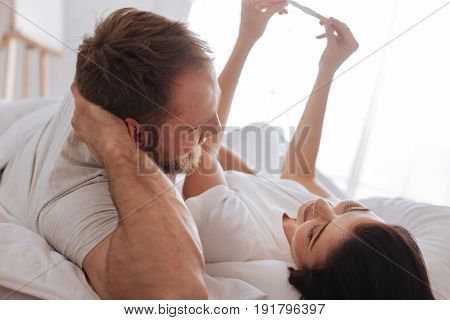 What will our baby look like. Newly married couple holding a positive pregnancy test and imagining their future baby together in the morning.