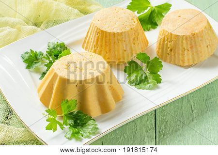 Tasty homemade carrot-chicken souffle cooked in double boiler. Souffle served on plate on green wooden table with yellow gauze napkin. Concept of dietary and healthy eating. Selective focus