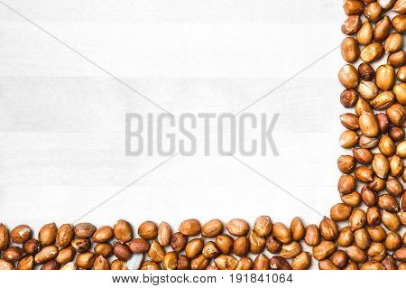 Peanut corner background. White wooden board or table with nut frame or border. Groundnut backdrop and template with copy space.