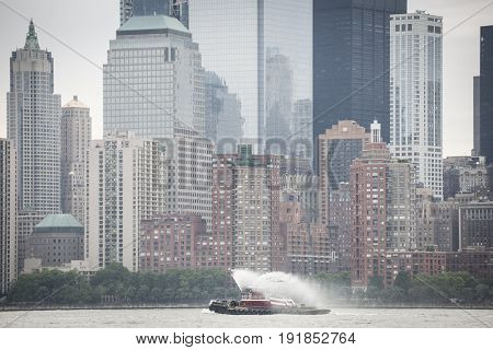 Eric McAllister harbor tugboat sprays water as it passes the Freedom Tower and World Trade Center Financial District at the Parade of Ships at start of Fleet Week New York, JERSEY CITY NJ MAY 24 2017.
