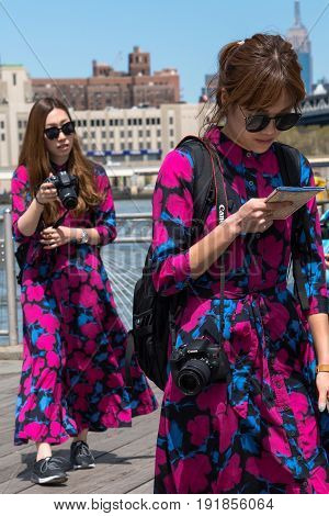 New York City United States - April 23 2017: Two asian women tourists dressing the same way walking at Dumbo waterfront.