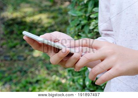 Woman hand using smart phone on green park background business and technology concept gen Z digital marketing lifestyle the internet of things social media network