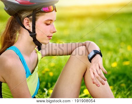 Woman traveling bicycle in summer park. Bicyclist girl watch on smart watch. Girl counts pulse after sport training. Kid is resting on nature at weekend. Sportswoman waiting for her friends.