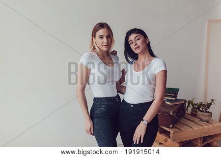 Two beautiful women in white T-shirts in studio. Mock-up.