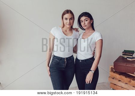 Two beautiful women in white T-shirts in studio. Mock-up.