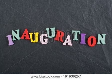 Iinauguration . English word on black board background composed from colorful abc alphabet block wooden letters, copy space for ad text. Learning english concept