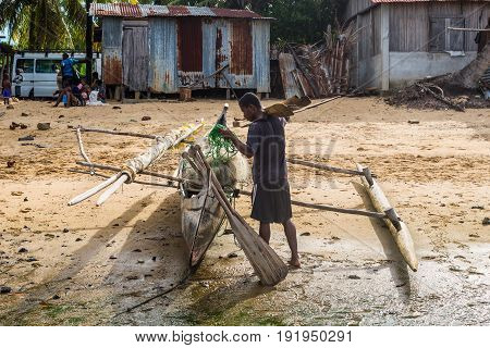 Ambatozavavy Nosy Be Madagascar - December 19 2015: Boatman and his traditional wood pirogue with outrigger in the fishing Ambatozavavy village on the Nosy Be island Madagascar.
