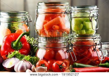 Jars With Marinated Food And Raw Vegetables On Cutting Board