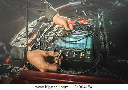 car diagnostic: hands of electrician connect the oscilloscope to the engine
