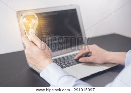 Young Woman Programmer Hand Holding Light Bulb, Woman Hands Coding And Programming On Screen Laptop,