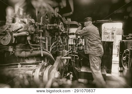 Engine Driver Working On Steam Train Engine In Monochrome