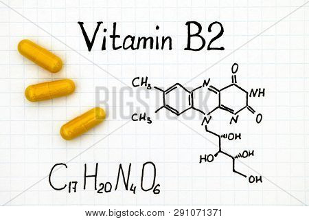 Chemical Formula Of Vitamin B2 And Yellow Pills. Close-up.