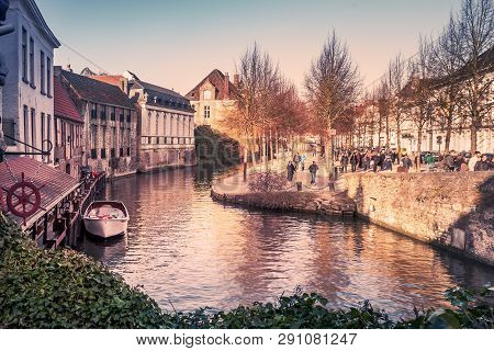 Bruges, Belgium - March 8, 2012. Historic Buildings, People Walking Along The Canal.