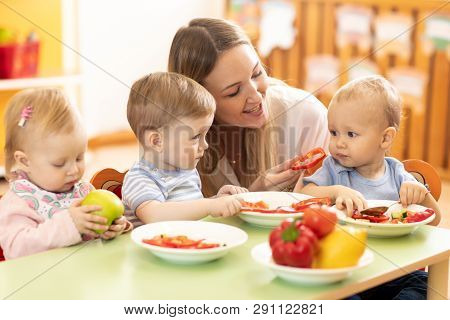 Babysitter Feeding Nursery Babies. Toddlers Eat Healthy Food In Daycare Center