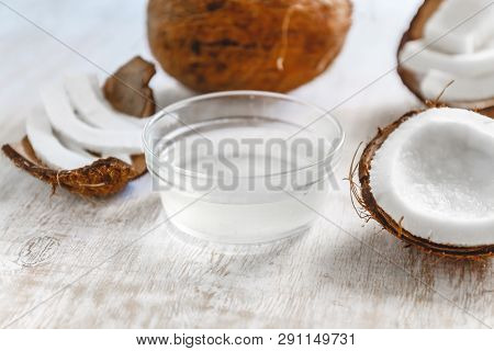 Whole Coconut Cut Into Chunks And Chips And Milk On A Light White Wooden Background. Top View.